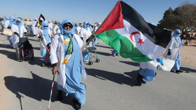 Manifestation de Sahraouis brandissant un drapeau du territoire devant une foule